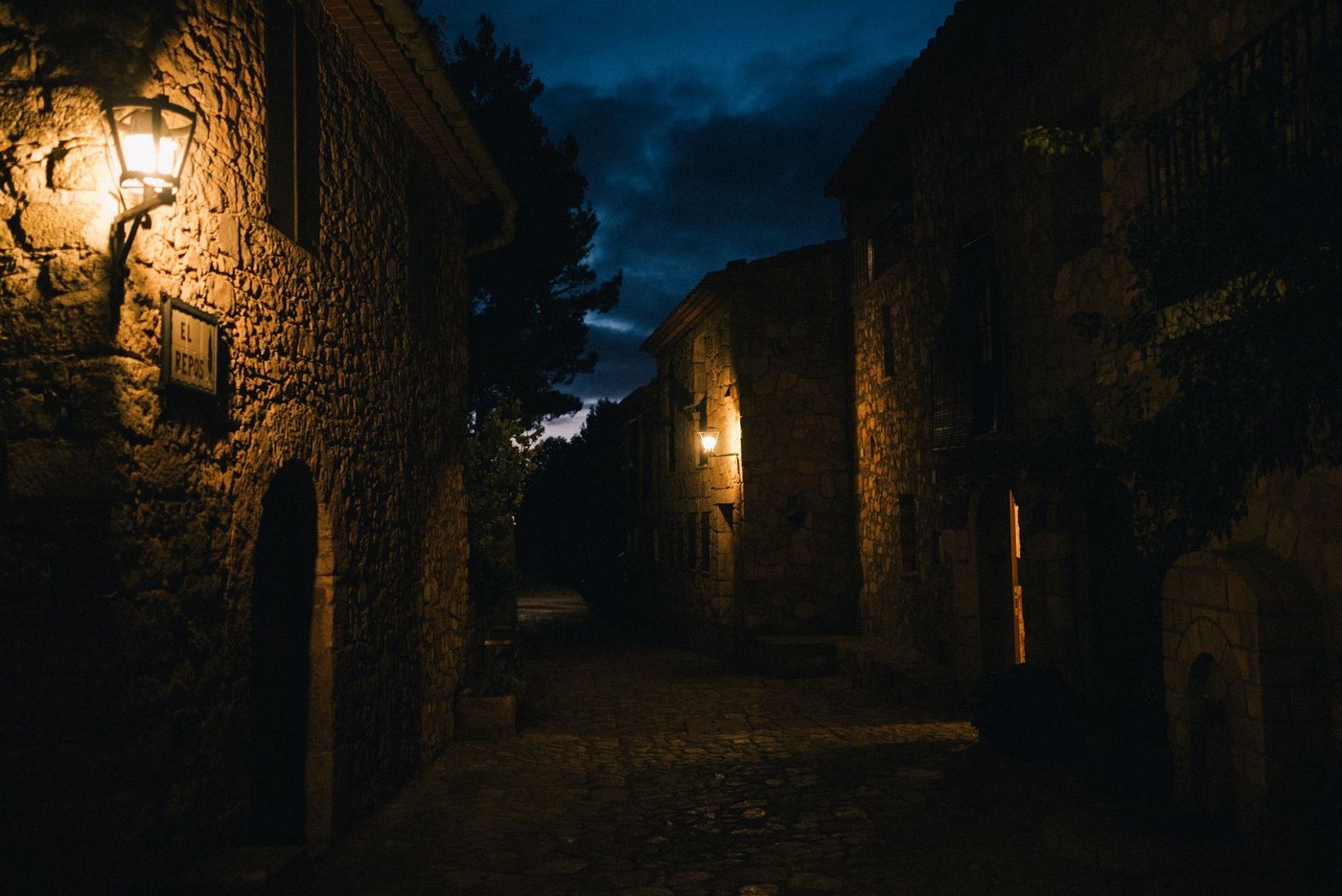 A lantern-lit street of close-set stone houses at night